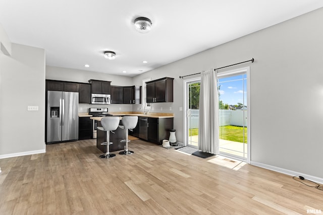 1604 Savile Ln, Washington, IL 61571 - kitchen featuring stainless steel appliances, light countertops, light wood-style flooring, a kitchen bar, and recessed lighting