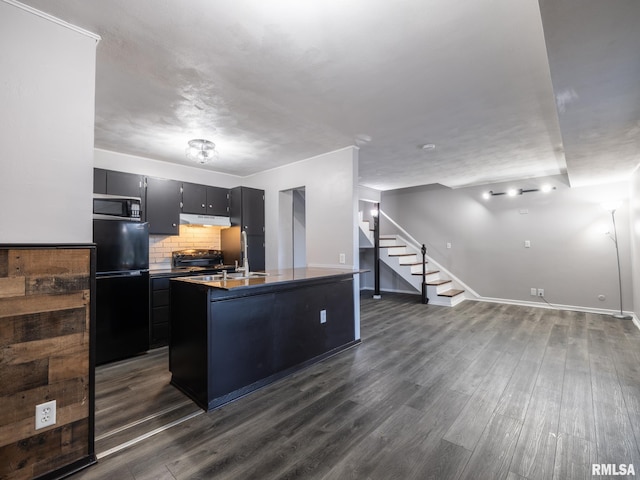 3119 W Willow Knolls Rd Unit 37B, Peoria, IL 61614 - kitchen with freestanding refrigerator, stainless steel microwave, under cabinet range hood, dark wood-style floors, and a center island with sink