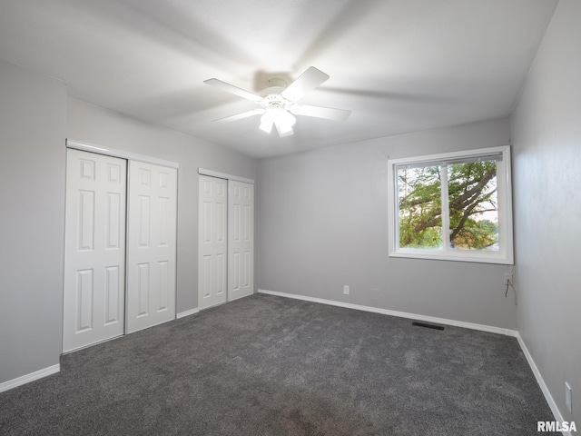 3119 W Willow Knolls Rd Unit 37B, Peoria, IL 61614 - unfurnished bedroom featuring multiple closets, dark colored carpet, and a ceiling fan