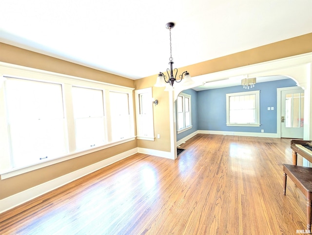 1101 S 4th St, Pekin, IL 61554 - unfurnished dining area featuring a chandelier, arched walkways, and wood finished floors
