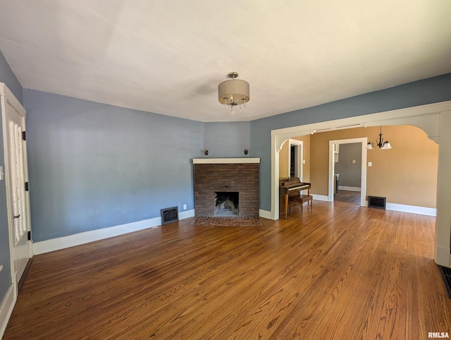 1101 S 4th St, Pekin, IL 61554 - unfurnished living room featuring a chandelier, arched walkways, and wood finished floors
