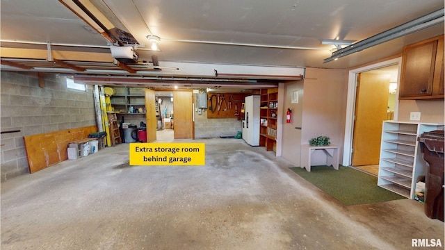 1729 W Willow Wood Dr, Peoria, IL 61614 - garage featuring a garage door opener, electric panel, concrete block wall, and freestanding refrigerator