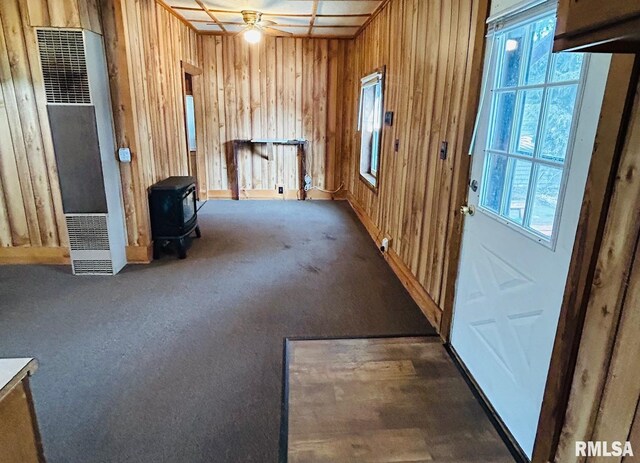 1305 S 8th St, Pekin, IL 61554 - carpeted empty room with a heating unit, a wood stove, ceiling fan, and wood walls