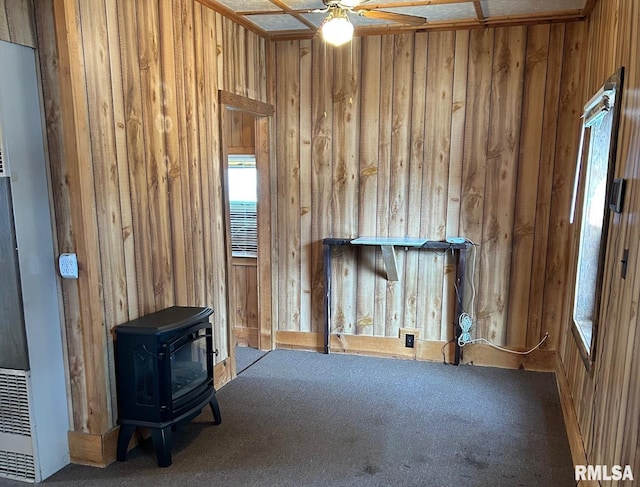 1305 S 8th St, Pekin, IL 61554 - unfurnished living room with a wood stove, wooden walls, carpet flooring, and ceiling fan
