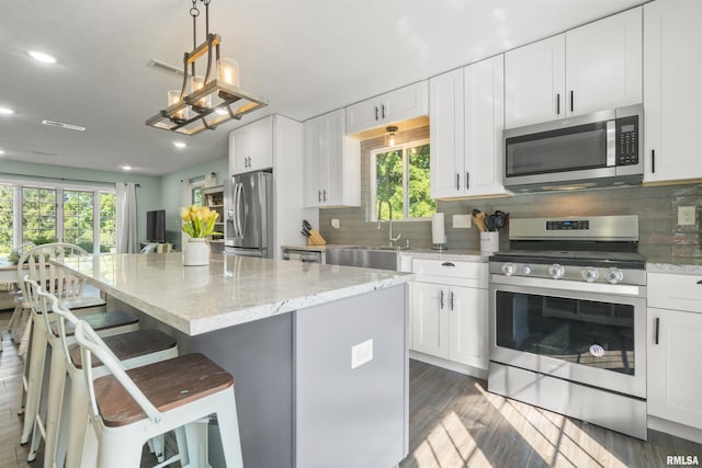276 E Far Hills Dr, East Peoria, IL 61611 - kitchen with appliances with stainless steel finishes, a center island, recessed lighting, backsplash, and dark wood-style flooring