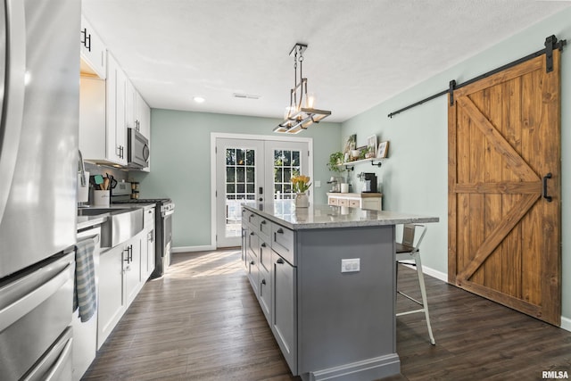 276 E Far Hills Dr, East Peoria, IL 61611 - kitchen with appliances with stainless steel finishes, a kitchen island, a barn door, a breakfast bar area, and dark wood finished floors
