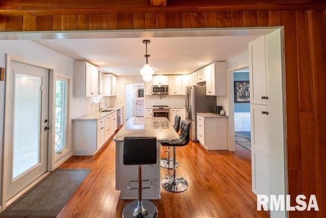 210 W Wolf Rd, Peoria, IL 61614 - kitchen with appliances with stainless steel finishes, light wood-type flooring, a breakfast bar, a kitchen island, and white cabinets