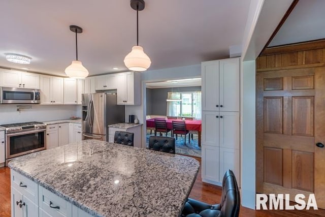 210 W Wolf Rd, Peoria, IL 61614 - kitchen with stainless steel appliances, light stone countertops, wood finished floors, and white cabinetry