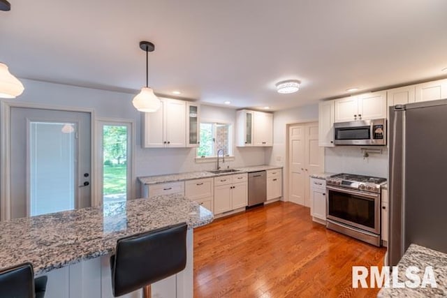 210 W Wolf Rd, Peoria, IL 61614 - kitchen featuring appliances with stainless steel finishes, glass insert cabinets, white cabinetry, light stone counters, and a kitchen bar