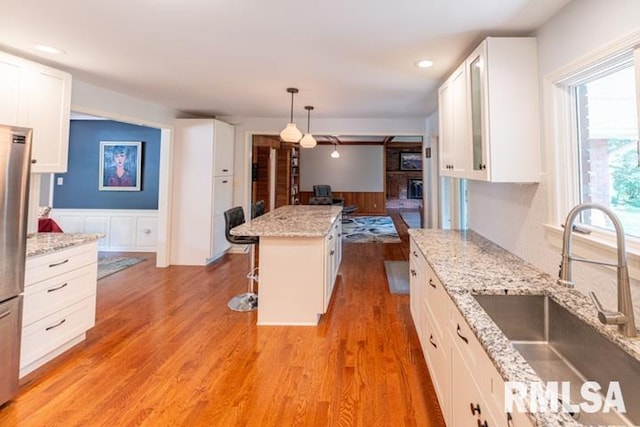 210 W Wolf Rd, Peoria, IL 61614 - kitchen with wainscoting, white cabinets, light wood-style flooring, a kitchen breakfast bar, and pendant lighting