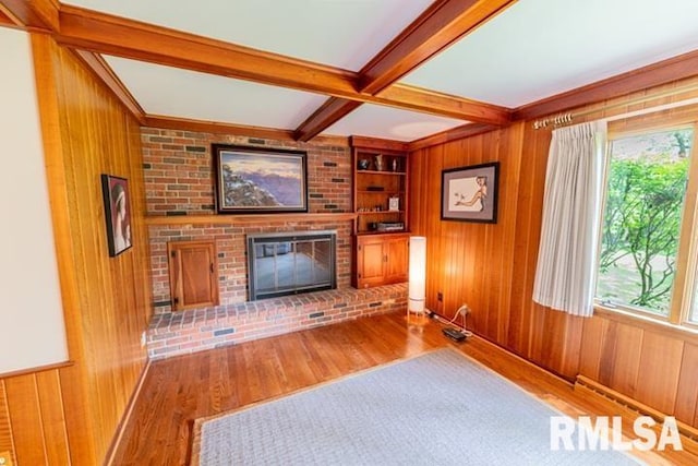 210 W Wolf Rd, Peoria, IL 61614 - unfurnished living room with wood walls, wood finished floors, beamed ceiling, plenty of natural light, and a fireplace