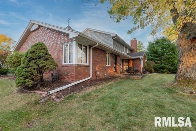 210 W Wolf Rd, Peoria, IL 61614 - view of property exterior with brick siding, a chimney, a lawn, and a patio area