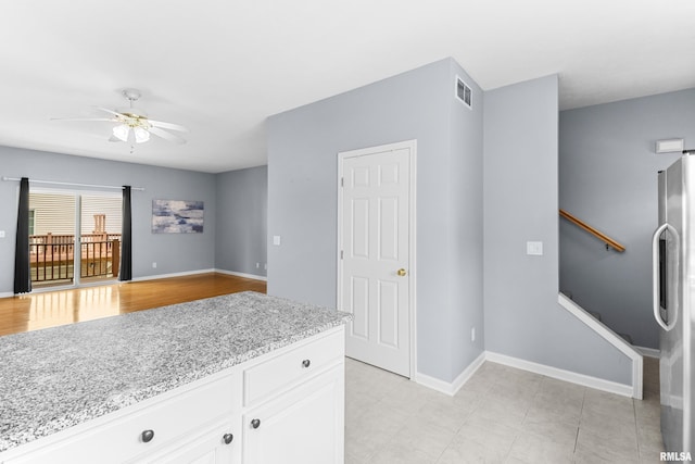 2024 S 2nd Ave, Morton, IL 61550 - kitchen with freestanding refrigerator, ceiling fan, white cabinets, and light stone counters