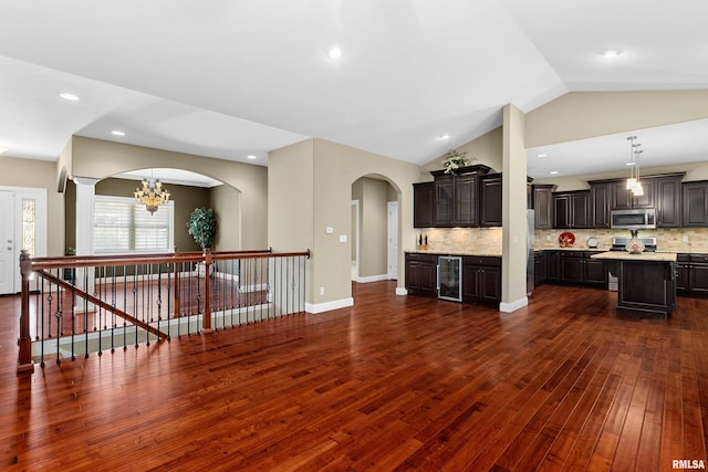 2627 W Lake Pointe Ter, Peoria, IL 61614 - unfurnished living room with beverage cooler, dark wood-type flooring, vaulted ceiling, arched walkways, and a chandelier