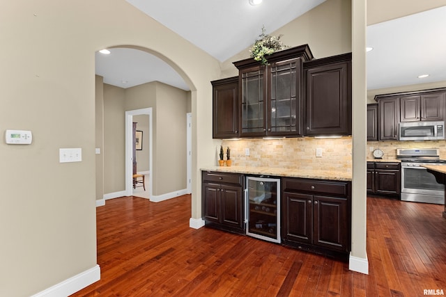 2627 W Lake Pointe Ter, Peoria, IL 61614 - indoor dry bar with appliances with stainless steel finishes, beverage cooler, arched walkways, backsplash, and dark wood-type flooring