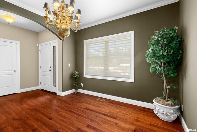 2627 W Lake Pointe Ter, Peoria, IL 61614 - unfurnished room featuring arched walkways, wood finished floors, a chandelier, and crown molding