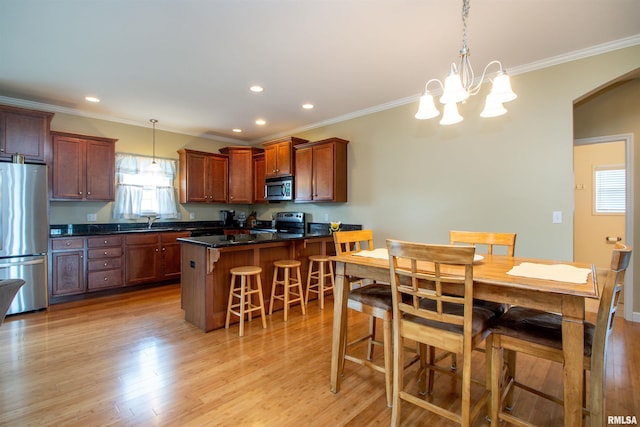 2203 W Gerald Ct, Peoria, IL 61615 - kitchen featuring appliances with stainless steel finishes, a kitchen breakfast bar, arched walkways, light wood-style floors, and ornamental molding