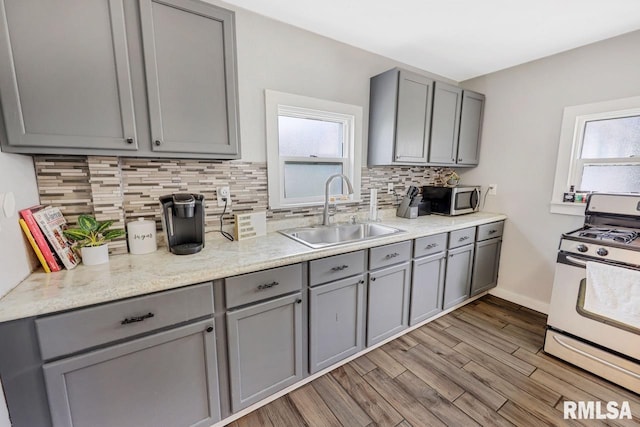 903 E Lake Ave, Peoria Heights, IL 61616 - kitchen featuring white gas range, gray cabinets, stainless steel microwave, backsplash, and plenty of natural light