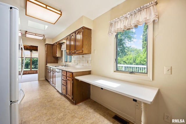 3524 W Saymore Ln, Peoria, IL 61615 - kitchen with freestanding refrigerator, light floors, light countertops, white dishwasher, and decorative backsplash