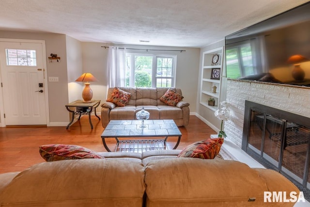 926 Birchwood Dr, Washington, IL 61571 - living room featuring built in features, wood finished floors, a textured ceiling, and a glass covered fireplace