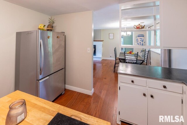 926 Birchwood Dr, Washington, IL 61571 - kitchen with freestanding refrigerator, wood finished floors, white cabinets, and a brick fireplace