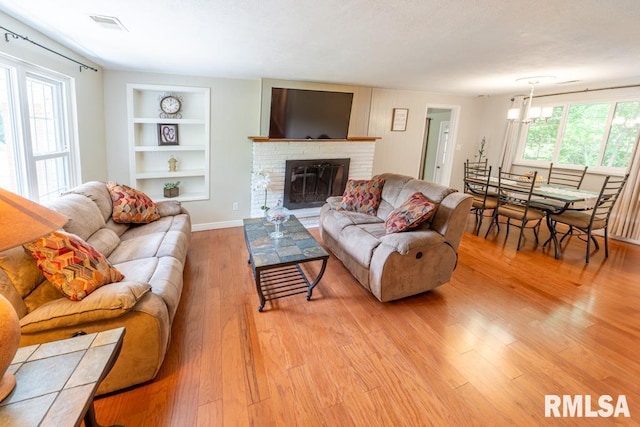 926 Birchwood Dr, Washington, IL 61571 - living area with built in features, light wood finished floors, a brick fireplace, and a chandelier