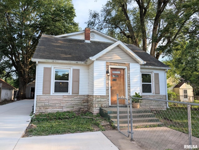 218 Meadow Lawn St, Manito, IL 61546 - view of front of house featuring stone siding, a fenced front yard, roof with shingles, and a gate