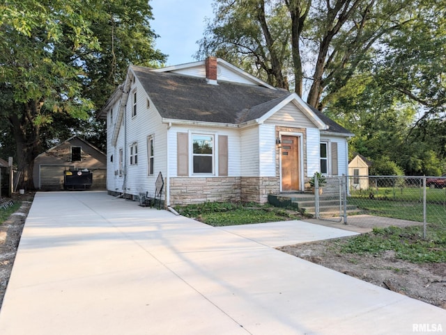 218 Meadow Lawn St, Manito, IL 61546 - view of front of home with stone siding, a chimney, roof with shingles, concrete driveway, and an outdoor structure