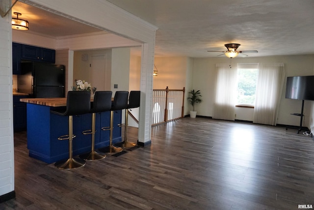 3406 W Brookside Dr, Peoria, IL 61615 - kitchen with freestanding refrigerator, blue cabinetry, a ceiling fan, dark wood-style flooring, and a kitchen bar