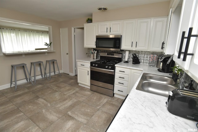4527 N Nelson Dr, Peoria, IL 61614 - kitchen featuring stainless steel appliances, decorative backsplash, white cabinetry, light countertops, and a kitchen bar