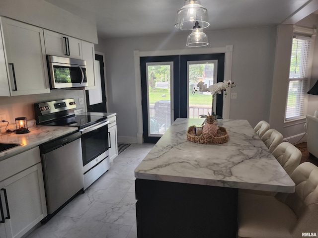 600 E Jefferson St, Washington, IL 61571 - kitchen featuring appliances with stainless steel finishes, light marble finish floors, a kitchen bar, and healthy amount of natural light