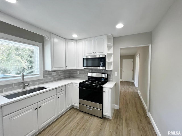 4914 N Bevalon Pl, Peoria, IL 61614 - kitchen featuring appliances with stainless steel finishes, open shelves, light wood-style floors, backsplash, and recessed lighting