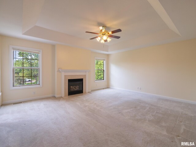 919 W Brookforest Dr, Peoria, IL 61615 - unfurnished living room with a tray ceiling, light colored carpet, a tile fireplace, and a ceiling fan