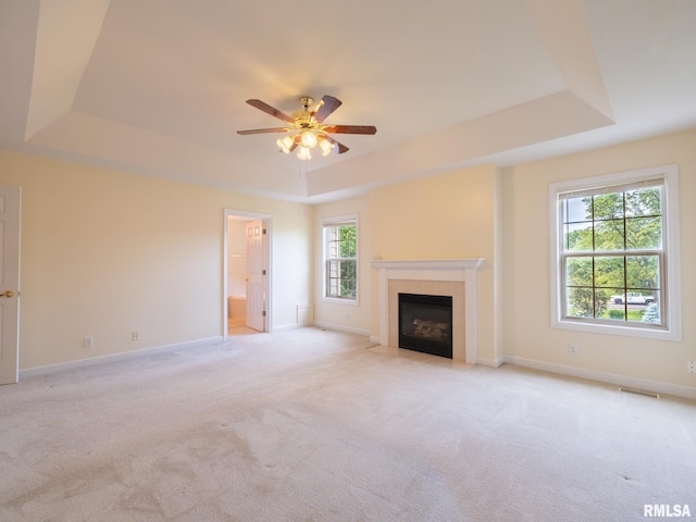 919 W Brookforest Dr, Peoria, IL 61615 - unfurnished living room featuring a tray ceiling, light colored carpet, a ceiling fan, and a tiled fireplace