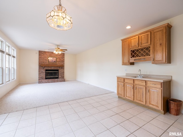 919 W Brookforest Dr, Peoria, IL 61615 - kitchen with light colored carpet, a ceiling fan, a brick fireplace, light countertops, and pendant lighting