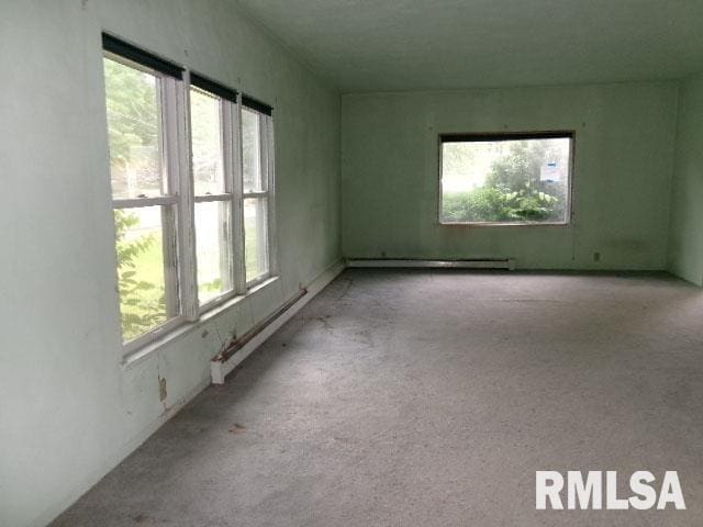 215 N Prairie St, Lacon, IL 61540 - carpeted empty room with plenty of natural light and a baseboard heating unit