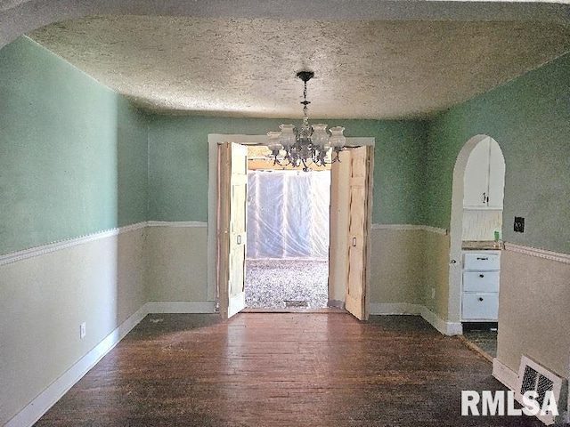246 E Myrtle St, Canton, IL 61520 - unfurnished dining area with wood finished floors, arched walkways, a chandelier, and a textured ceiling