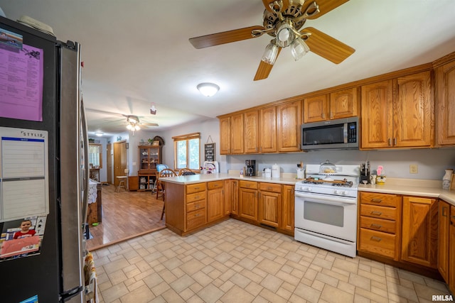611 E Ash St, Canton, IL 61520 - kitchen with stainless steel appliances, a peninsula, a ceiling fan, brick patterned flooring, and brown cabinetry
