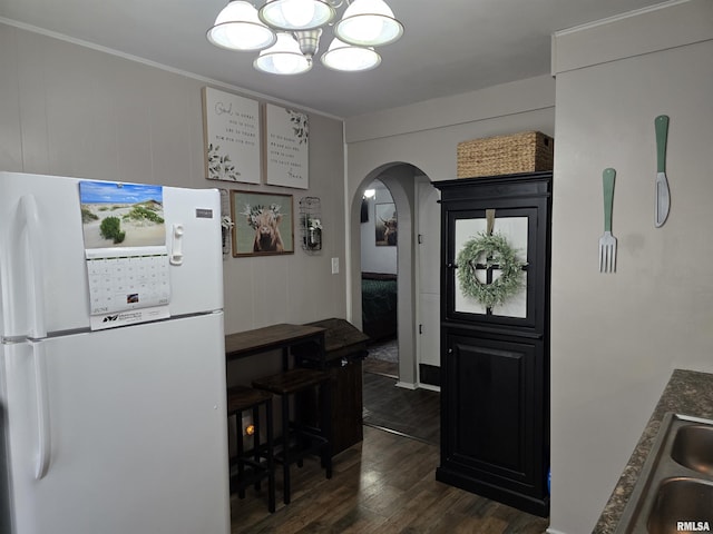 270 Thompson Ct, Canton, IL 61520 - kitchen featuring freestanding refrigerator, dark wood-style flooring, a chandelier, arched walkways, and ornamental molding