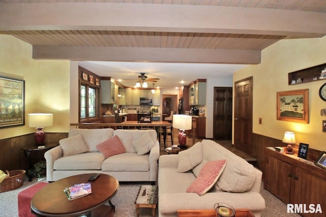 1402 W Grandridge Dr, Dunlap, IL 61525 - carpeted living area with a wooden ceiling with exposed beams, a wainscoted wall, wooden walls, and ceiling fan