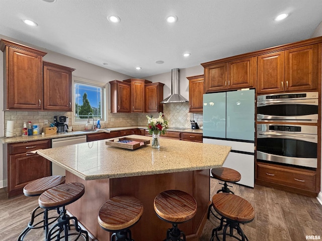 11030 N Ruby Ct, Dunlap, IL 61525 - kitchen with freestanding refrigerator, wall chimney exhaust hood, light wood-style floors, a kitchen breakfast bar, and recessed lighting