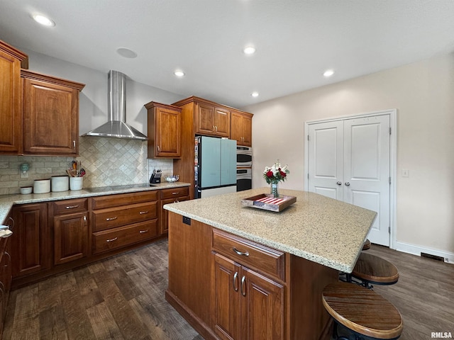 11030 N Ruby Ct, Dunlap, IL 61525 - kitchen with wall chimney exhaust hood, freestanding refrigerator, dark wood-type flooring, a breakfast bar area, and a center island