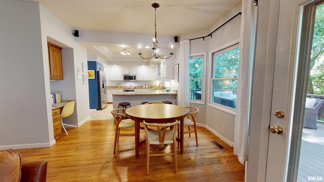 1119 W Brookforest Dr, Peoria, IL 61615 - dining area with a chandelier, light wood-style flooring, and a tray ceiling