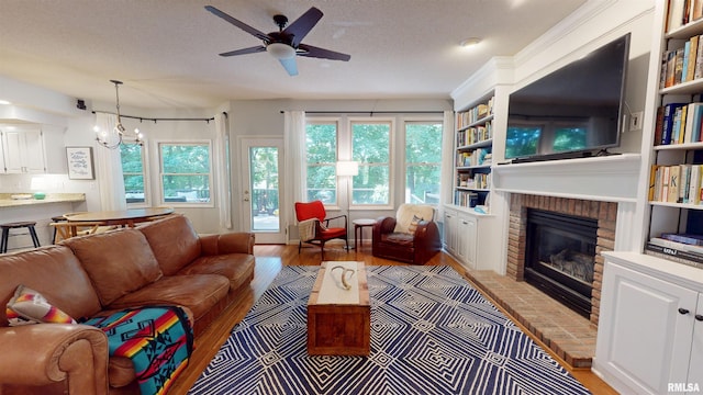 1119 W Brookforest Dr, Peoria, IL 61615 - living room with ceiling fan, a brick fireplace, light wood-type flooring, a chandelier, and built in shelves
