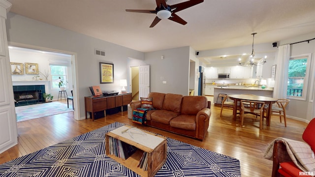 1119 W Brookforest Dr, Peoria, IL 61615 - living area featuring light wood-style floors, a chandelier, a tiled fireplace, and ceiling fan