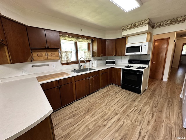 2401 Springfield Rd, East Peoria, IL 61611 - kitchen with gas stove, white microwave, light countertops, and light wood-style flooring