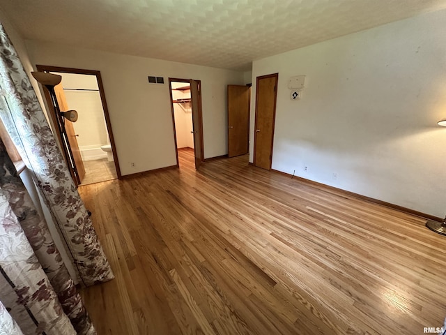 2401 Springfield Rd, East Peoria, IL 61611 - unfurnished bedroom with wood finished floors, ensuite bathroom, and a walk in closet
