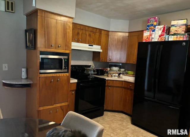 1104 S 8th St, Pekin, IL 61554 - kitchen featuring black appliances, under cabinet range hood, brown cabinets, and light countertops