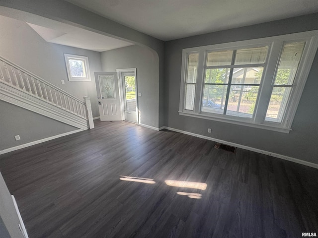 512 Fairholm Ave, Peoria, IL 61603 - unfurnished living room with arched walkways, dark wood-type flooring, and stairway