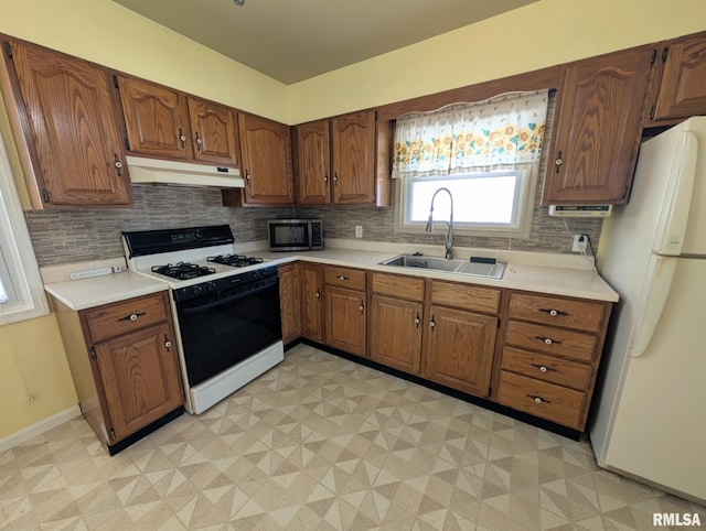 1427 Matilda St, Pekin, IL 61554 - kitchen with gas range, freestanding refrigerator, under cabinet range hood, stainless steel microwave, and tasteful backsplash